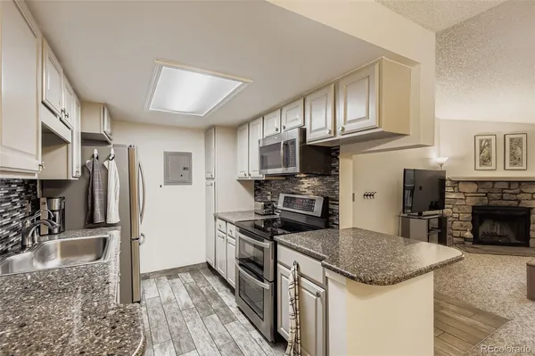 a kitchen with stainless steel appliances granite countertop a stove top oven a sink and a refrigerator