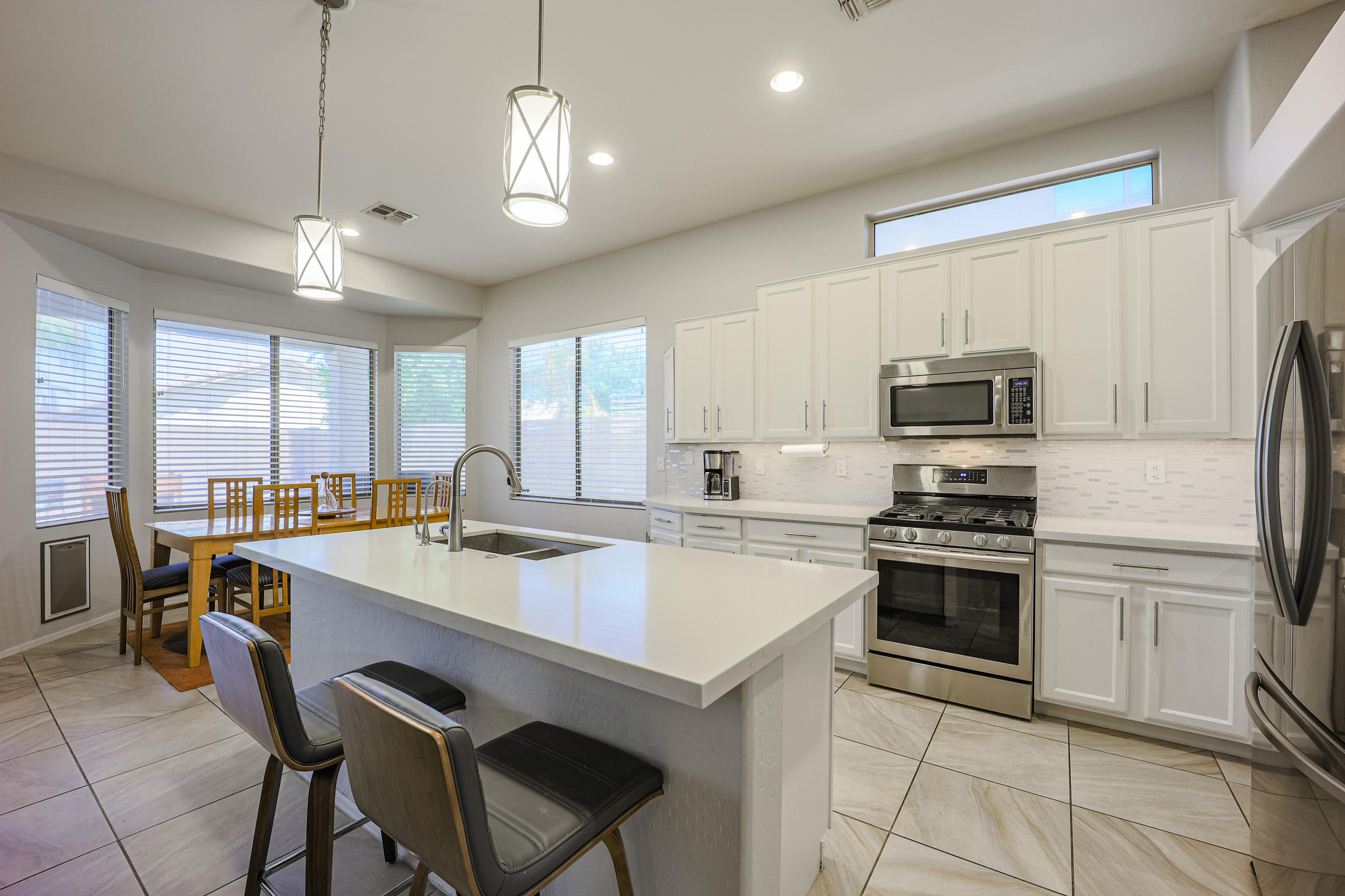 464 East Ranch Road Gilbert, AZ 85296 - Photo 7 of 21 a kitchen with a stove a sink dishwasher a refrigerator with a dining table and chairs