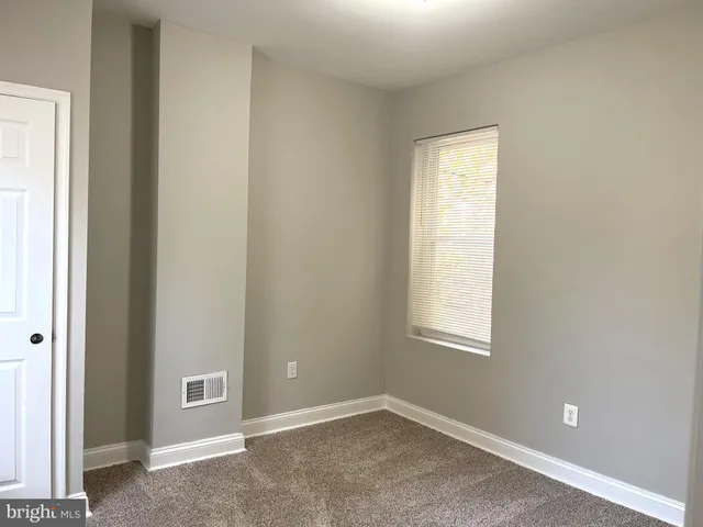 a view of an empty room with closet and a window