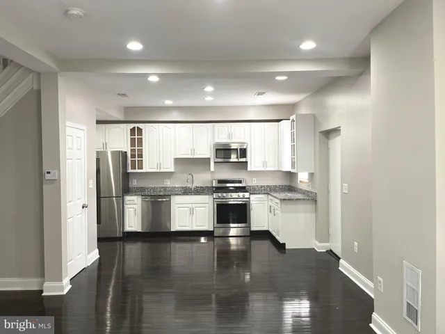 a kitchen with stainless steel appliances granite countertop a refrigerator and a stove top oven