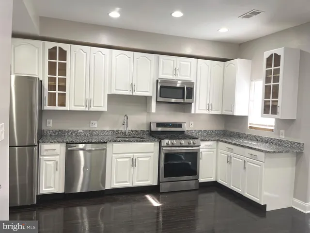 a kitchen with stainless steel appliances granite countertop a stove a sink and a microwave