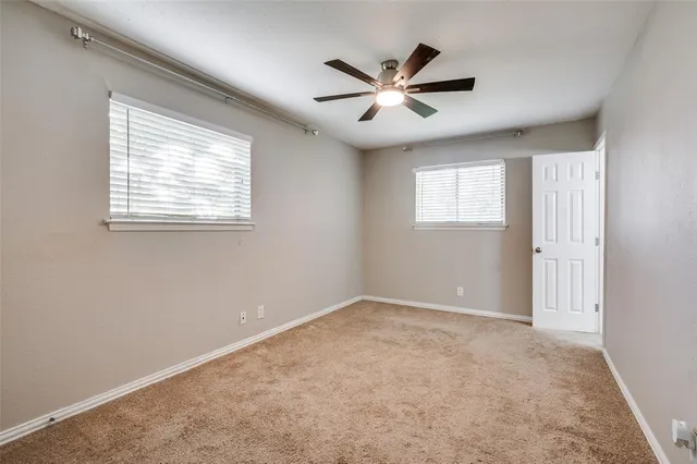 a view of an empty room with chandelier fan and fire place