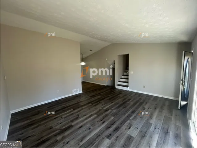 a view of an empty room with wooden floor and a fireplace