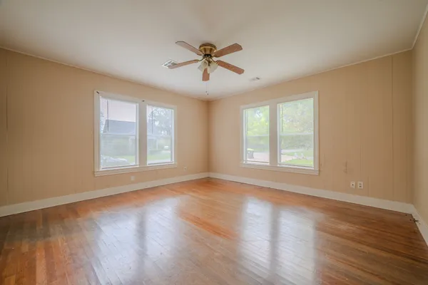 a view of empty room with wooden floor and fan