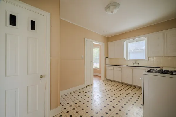 a kitchen with granite countertop a refrigerator a sink and white cabinets
