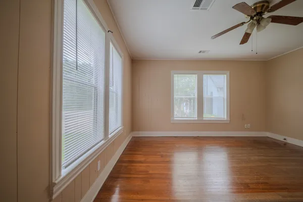 a view of an empty room with wooden floor and a window