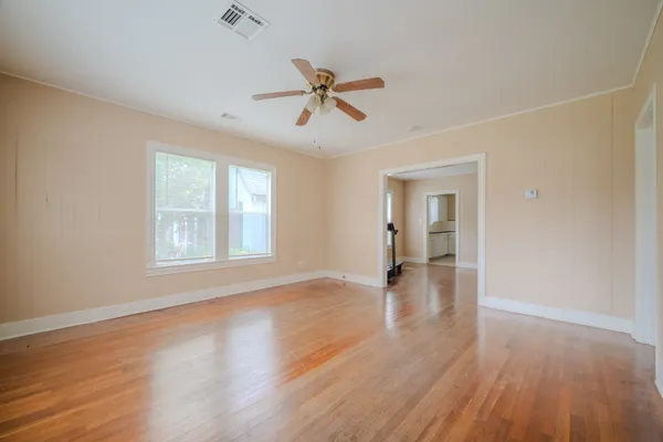 an empty room with wooden floor and windows
