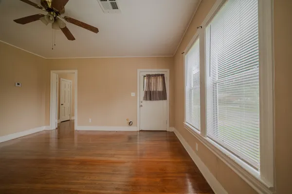 a view of an empty room with wooden floor and a window