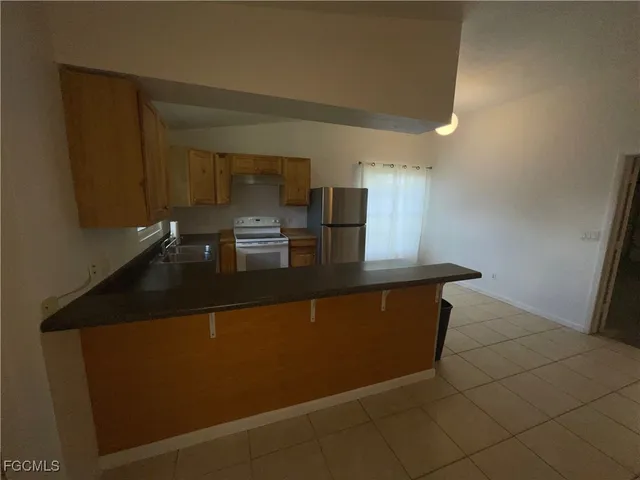 a kitchen with granite countertop a sink a stove top oven and cabinetry