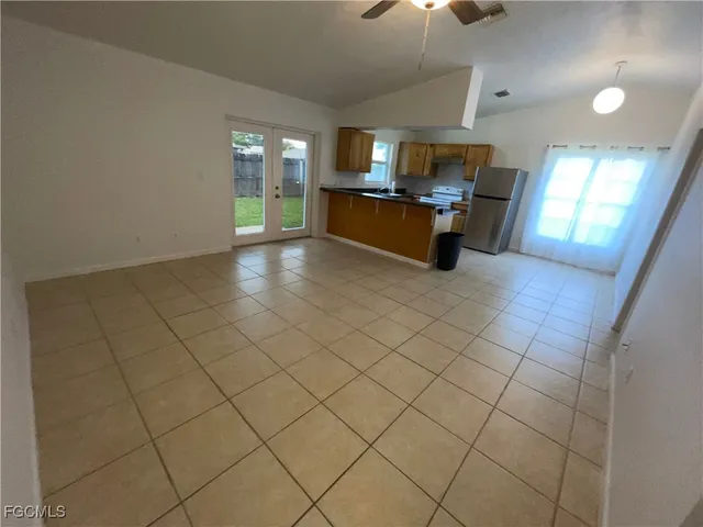 an empty room with kitchen and chandelier fan