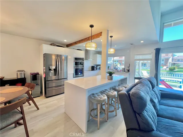a living room with furniture a refrigerator and kitchen view