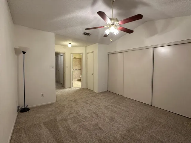 an empty room with closet and a chandelier fan