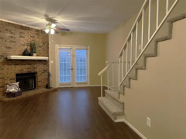 a view of a livingroom with wooden floor a fireplace and entryway