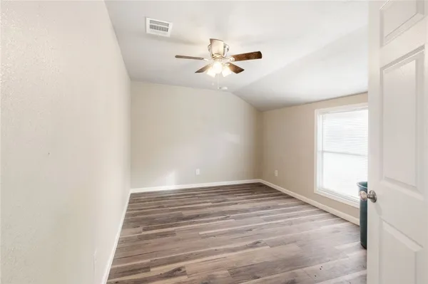 a view of empty room with window and ceiling fan
