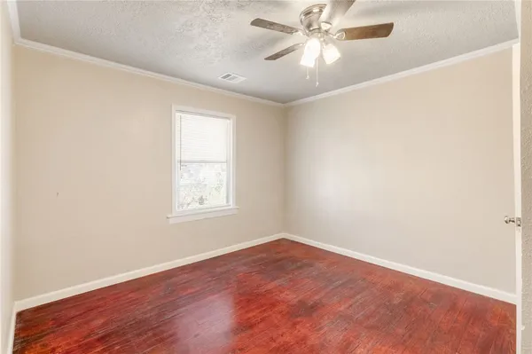 an empty room with wooden floor fan and windows