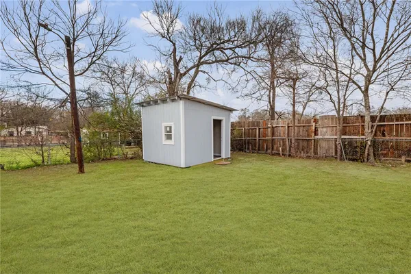 a backyard of a house with large trees and brick wall