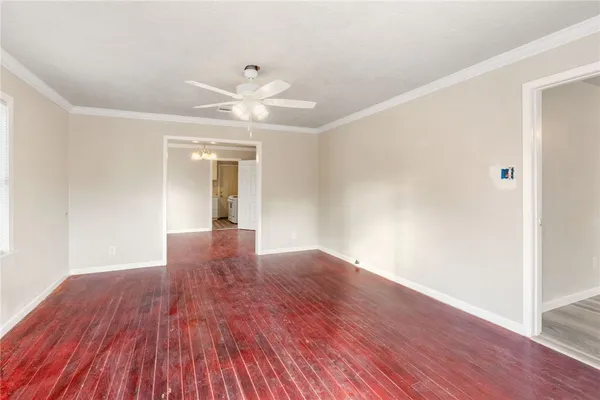 a view of an empty room with wooden floor and a ceiling fan