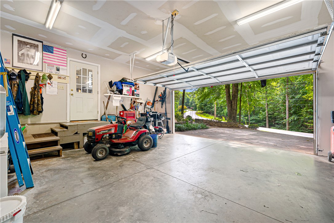 139 Tulip Lane Westminster, SC 29693 - Photo 18 of 37 A spacious garage, ready for your vehicles or projects, opens to a lush, tree-lined landscape.