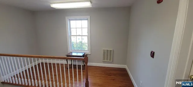 a view of a hallway with wooden floor and cabinet