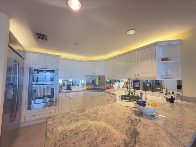 a view of a kitchen with kitchen island a counter top space a sink stainless steel appliances and cabinets