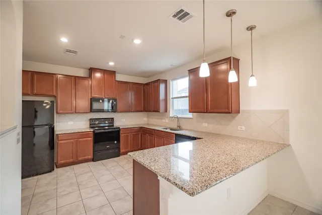 a large kitchen with stainless steel appliances granite countertop a refrigerator a sink a stove and a granite counter tops