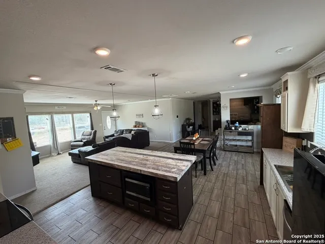 a large kitchen with kitchen island a stove a sink dishwasher and a dining table with the living room view