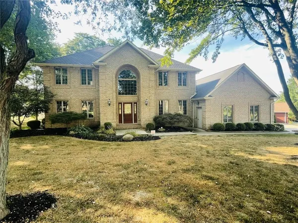 a view of a white house with a yard and large tree