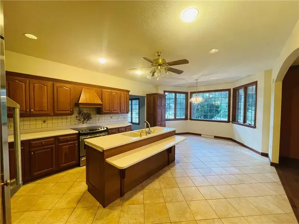 a large kitchen with stainless steel appliances granite countertop a stove and a view of living room