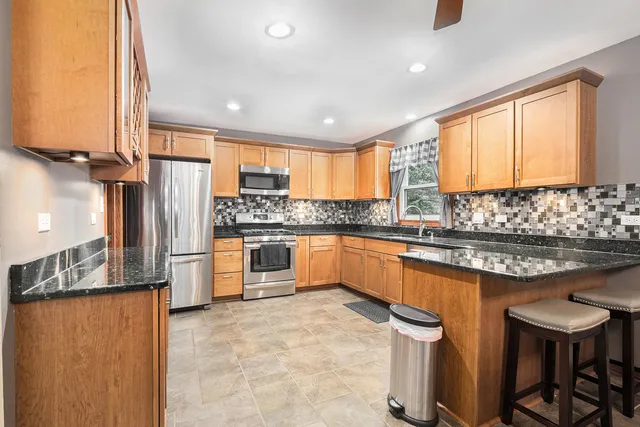 a kitchen with stainless steel appliances granite countertop a stove a sink and a refrigerator