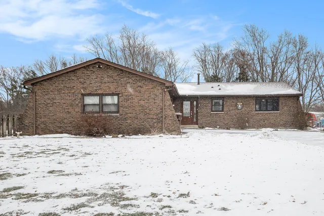 a front view of a house with a yard covered in snow