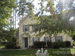 a front view of a house with a garden and trees