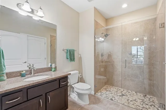 a bathroom with a granite countertop toilet a sink a mirror a shower a vanity and window