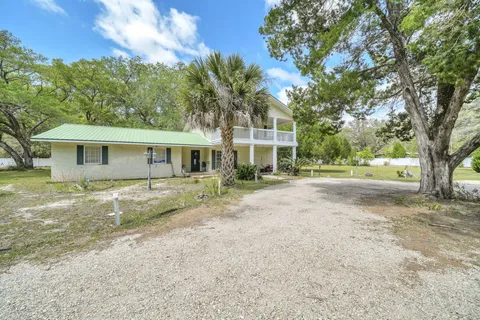 a view of a house with a yard and large tree