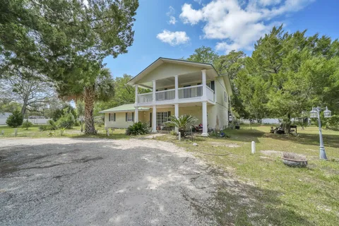 a view of a house with a yard and large trees
