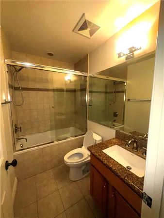a bathroom with a granite countertop sink toilet mirror and shower