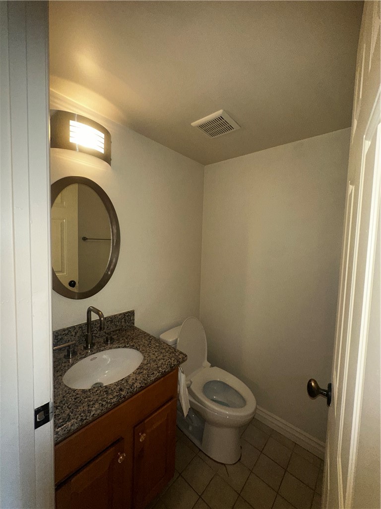 9356 19th Street, Unit D Rancho Cucamonga, CA 91701 - Photo 9 of 16 a bathroom with a granite countertop toilet a sink and a mirror
