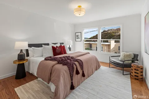 a spacious bedroom with a bed and wooden floor