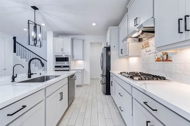 a kitchen with white cabinets sink and stainless steel appliances