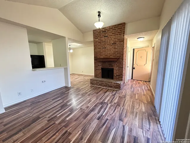 a view of empty room with wooden floor and fireplace