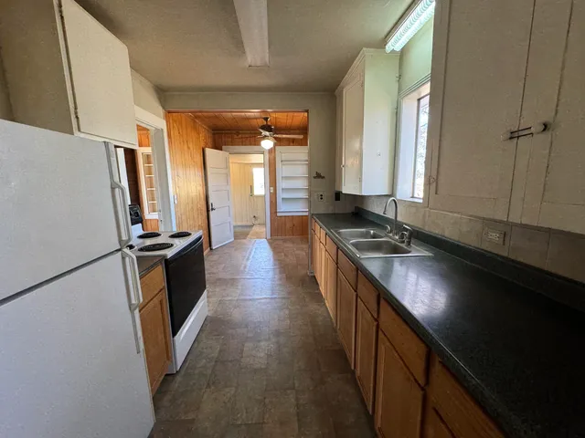 a kitchen with granite countertop a refrigerator a sink a stove and a refrigerator