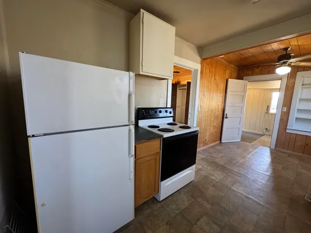 a view of kitchen with stainless steel appliances refrigerator stove and wooden floor