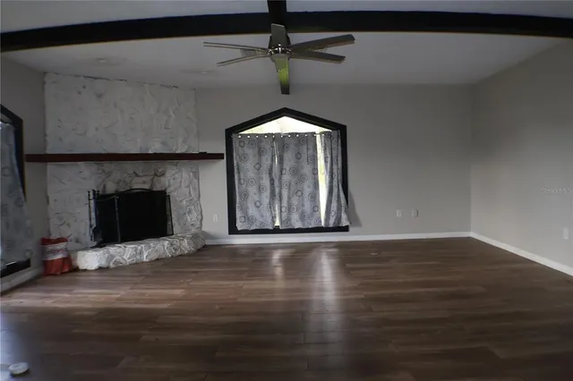 a living room with wooden floor a fireplace and a chandelier fan