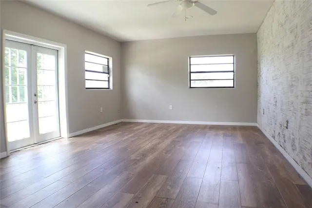 an empty room with wooden floor and windows