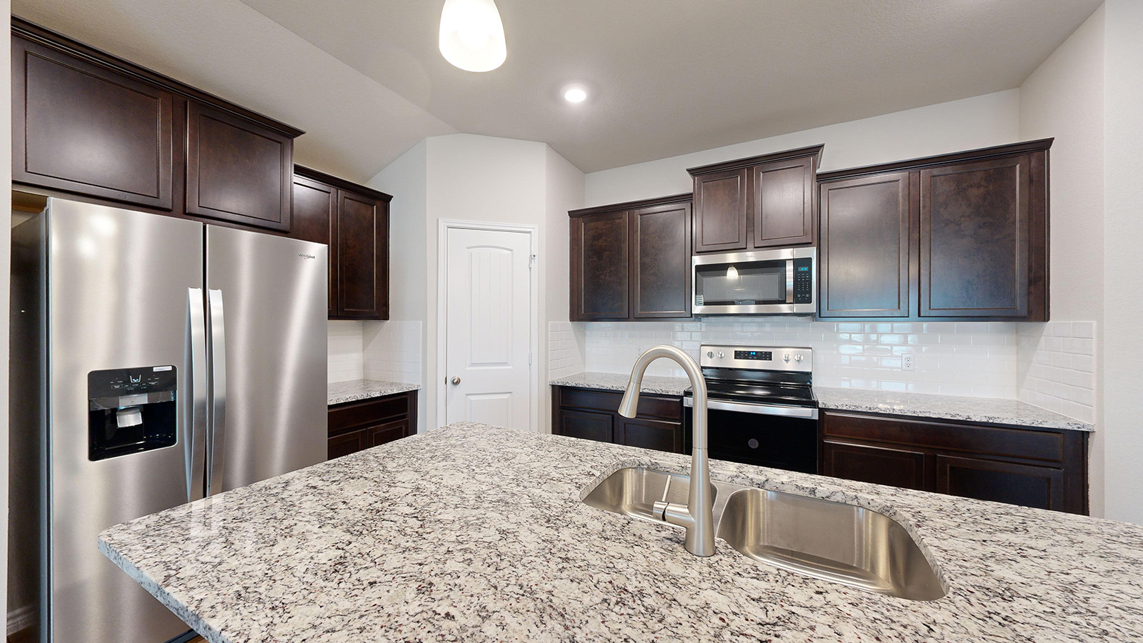 243 Water Wl Road Burnet, TX 78611 - Photo 5 of 23 Kitchen featuring a large island with a double basin sink, speckled countertop, and brushed nickel faucet