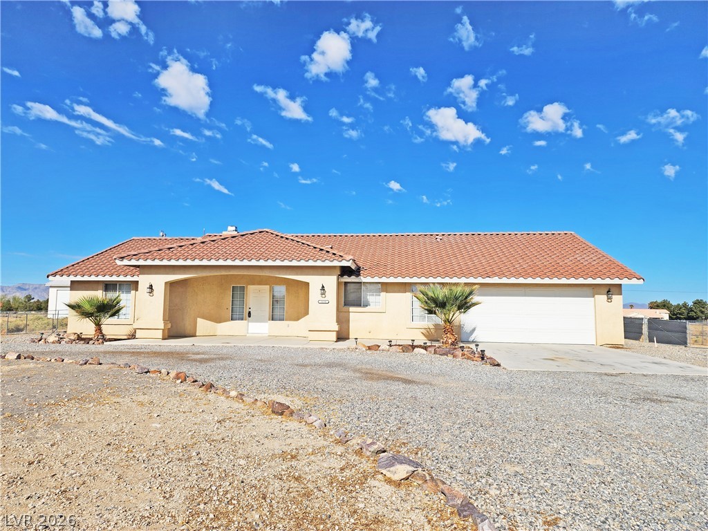 Mediterranean / spanish-style home with a tiled roof, driveway, fence, a garage, and stucco siding