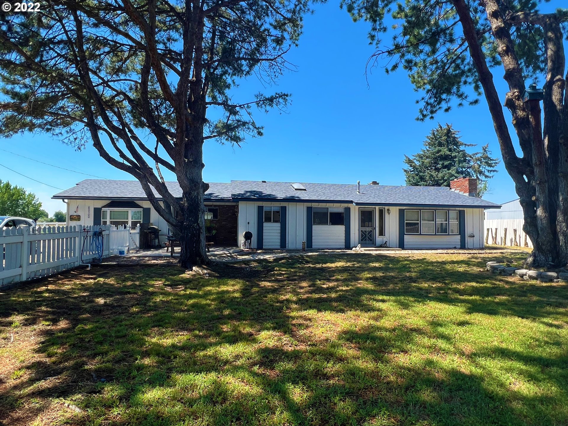 80500 Craig Road Hermiston, OR 97838 - Photo 1 of 24 a house that has a big yard large trees with wooden fence