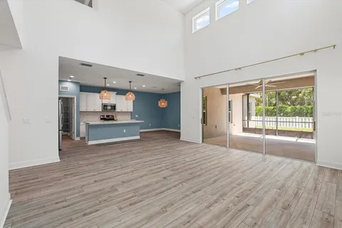 a view of empty room with wooden floor and kitchen view