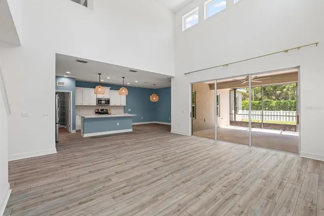 a view of empty room with wooden floor and kitchen view