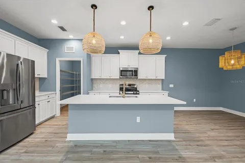 a view of a kitchen with kitchen island stainless steel appliances a sink and wooden floor