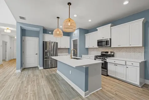 a kitchen with stainless steel appliances a stove top oven a refrigerator cabinets and wooden floor